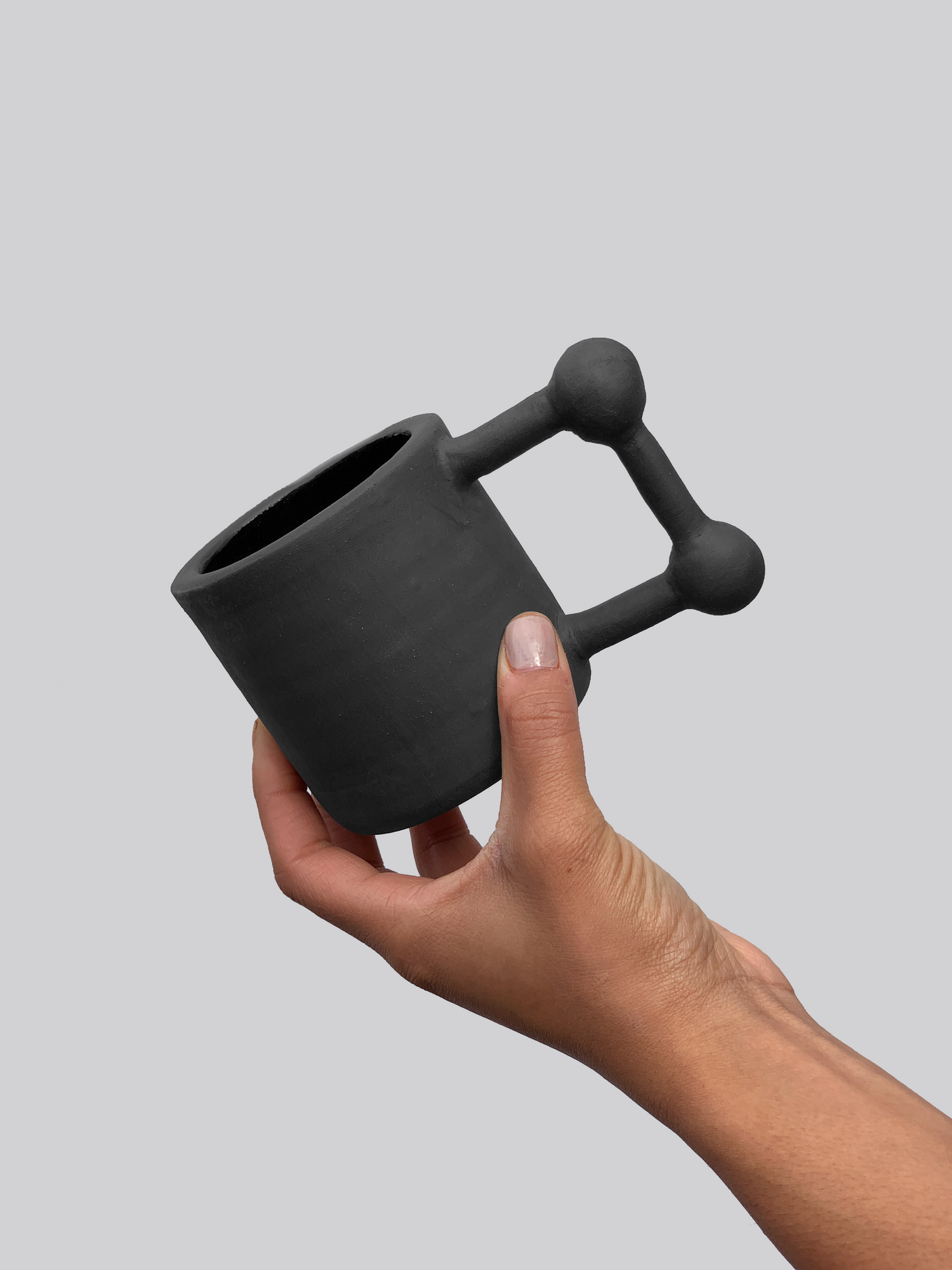 Black matte stoneware ceramic mug with a square shape and ball accents on the corners of the handle.