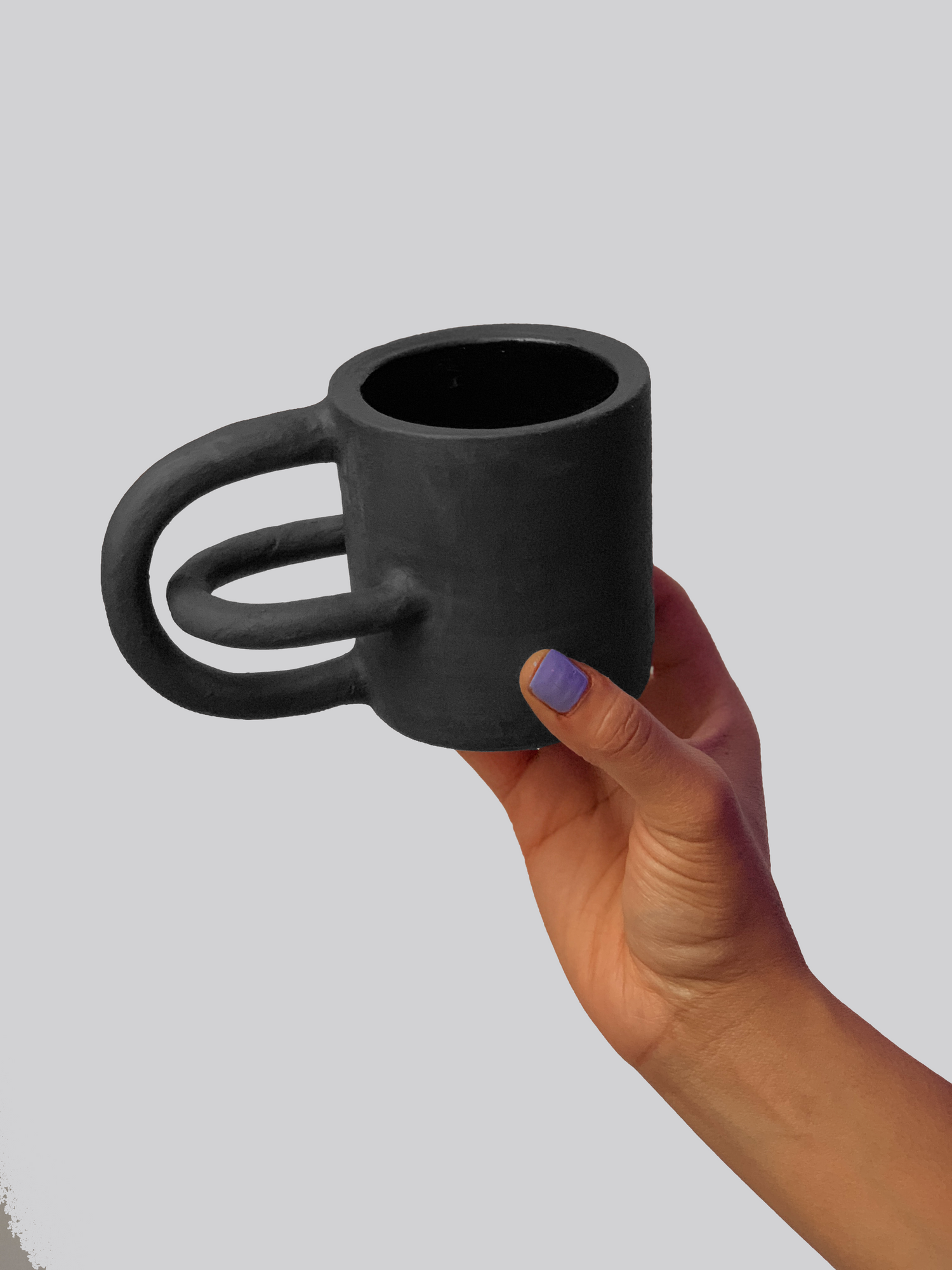 Black matte stoneware ceramic mug with intersecting arches as the handle.