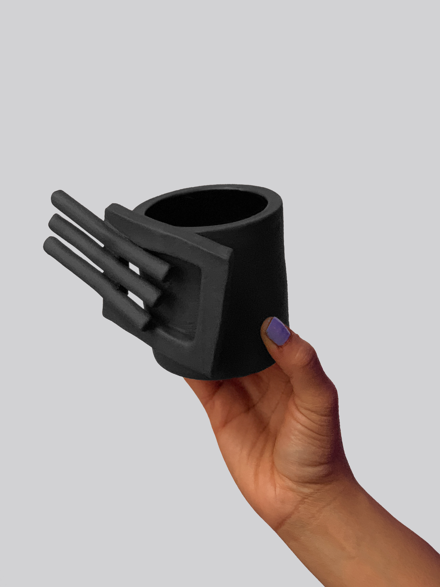 Black matte stoneware ceramic mug with an extended square on the side of the mug and three bars projecting outwards as the handle. 