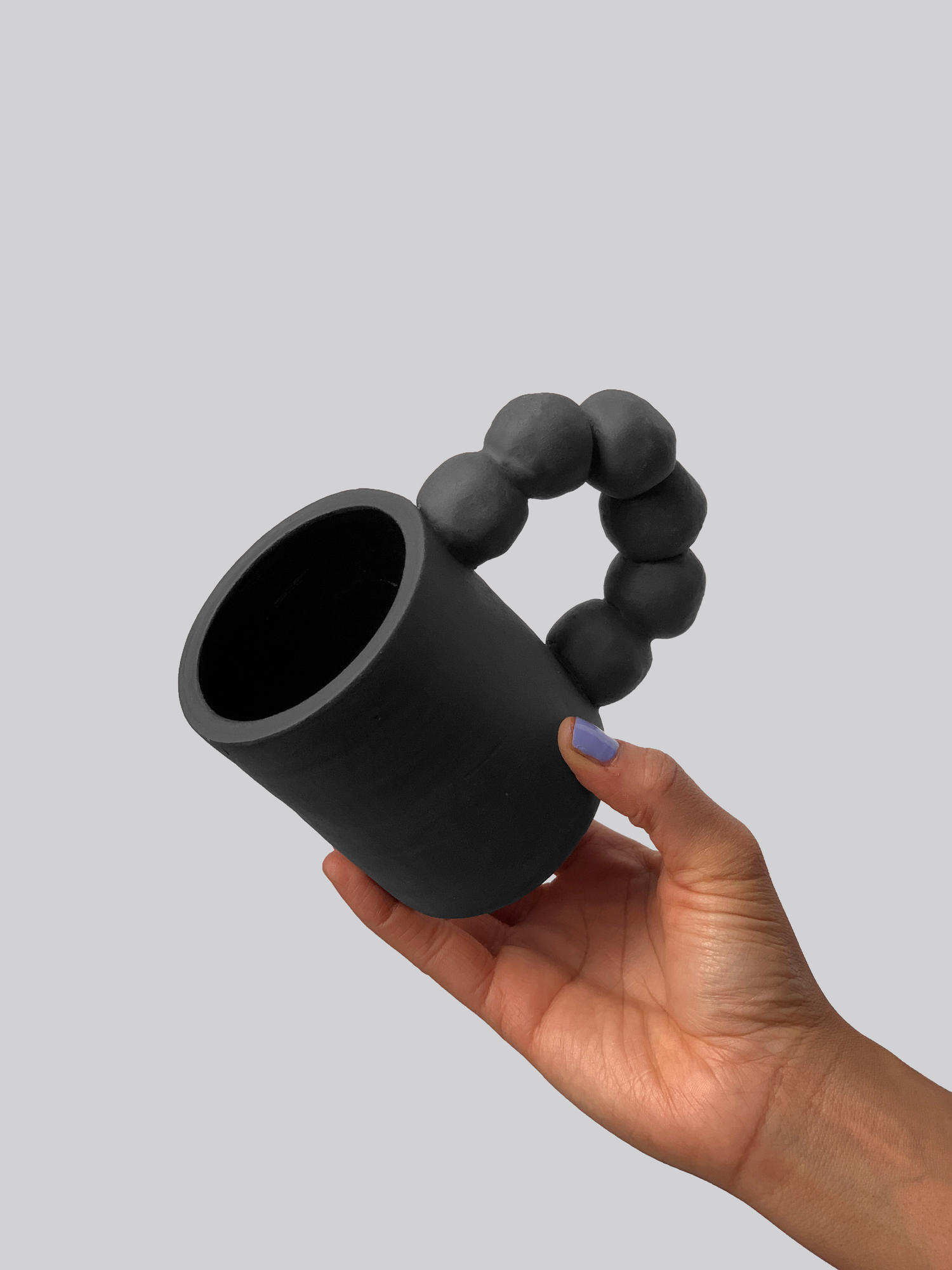 Black matte stoneware ceramic mug with six connected balls forming the handle.