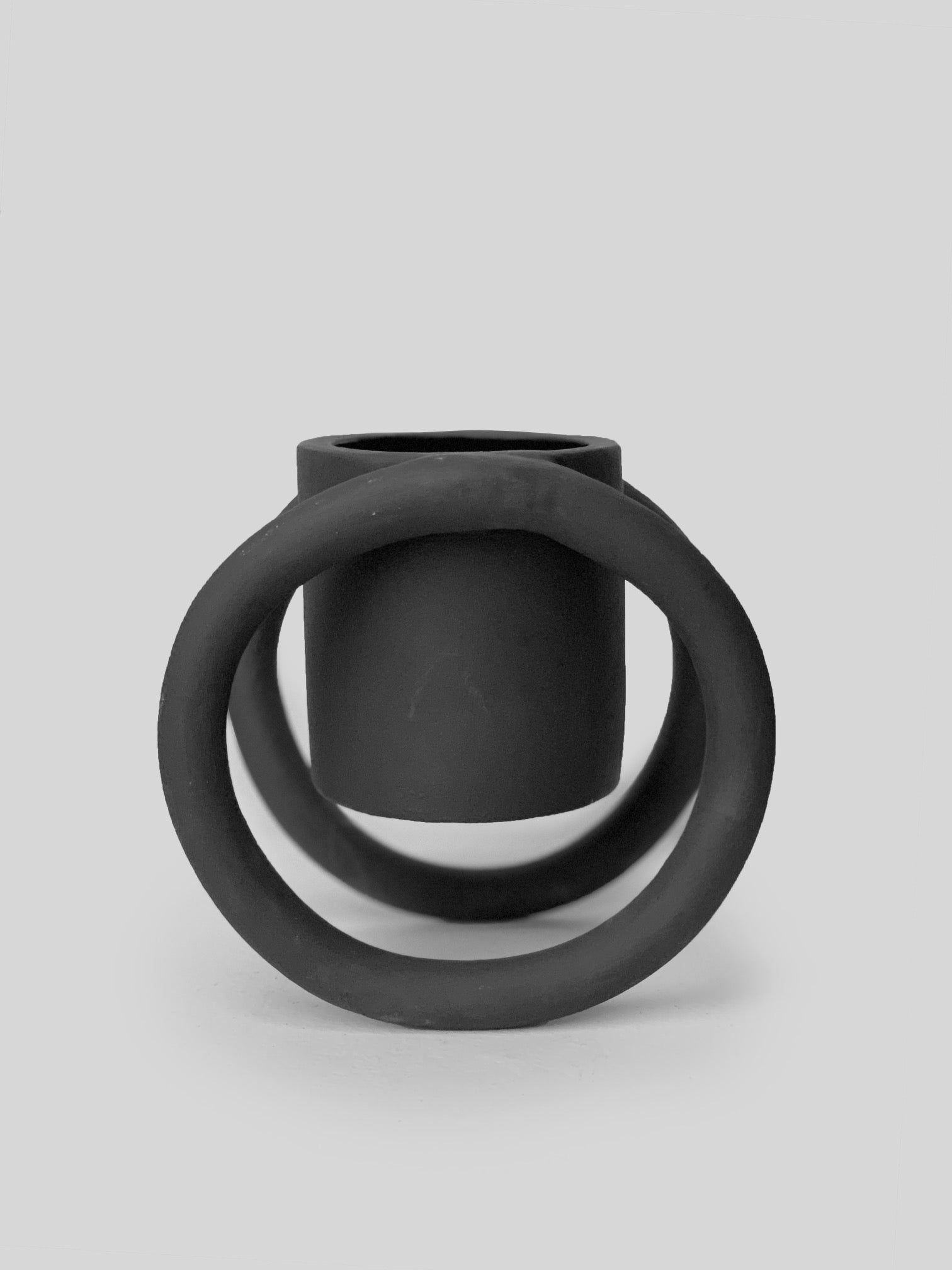 Black matte stoneware ceramic mug suspended from a circular disc on each side of the mug as the handles.