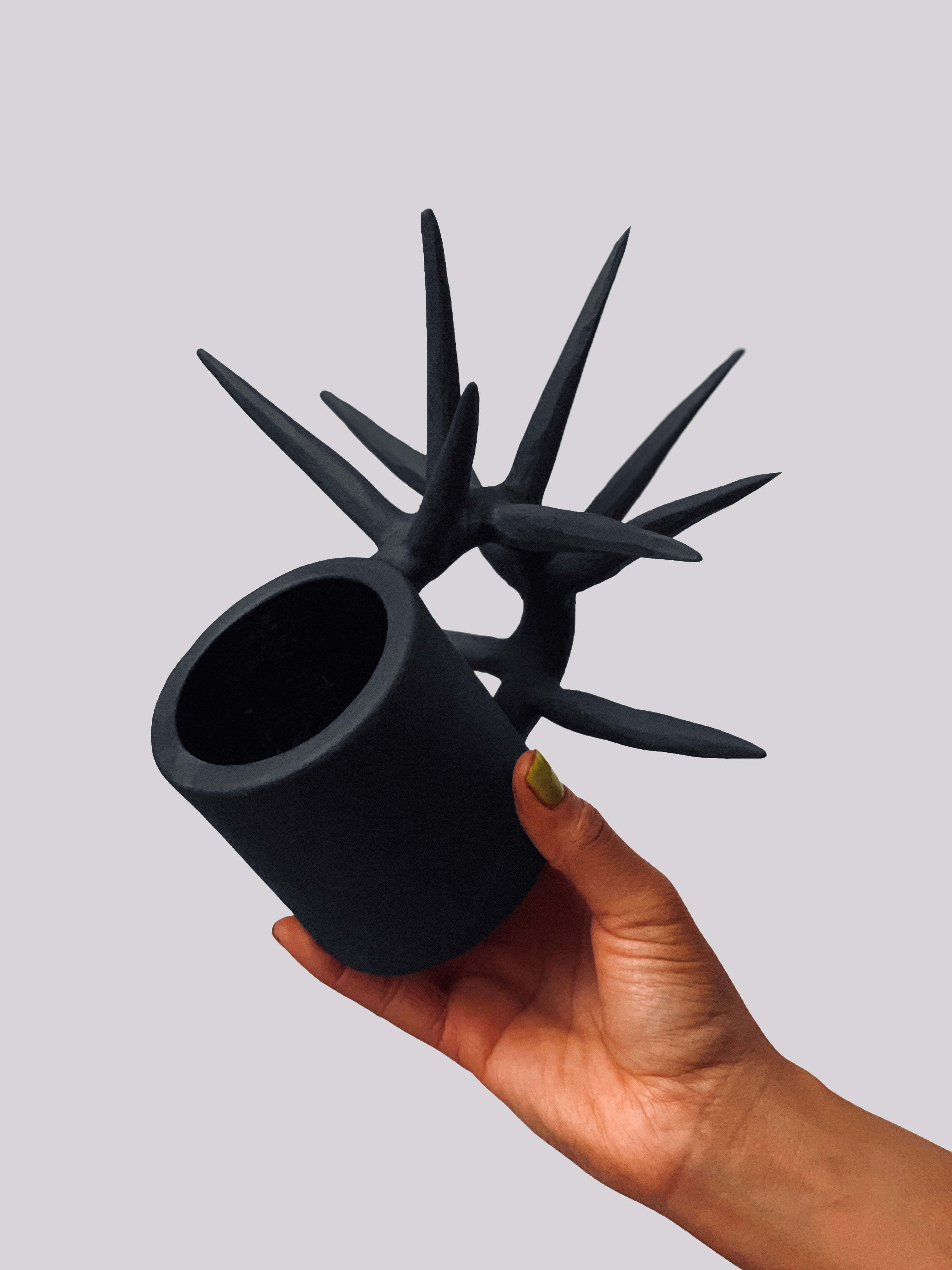 Black matte stoneware ceramic mug with long spikes extending from a circular side handle.