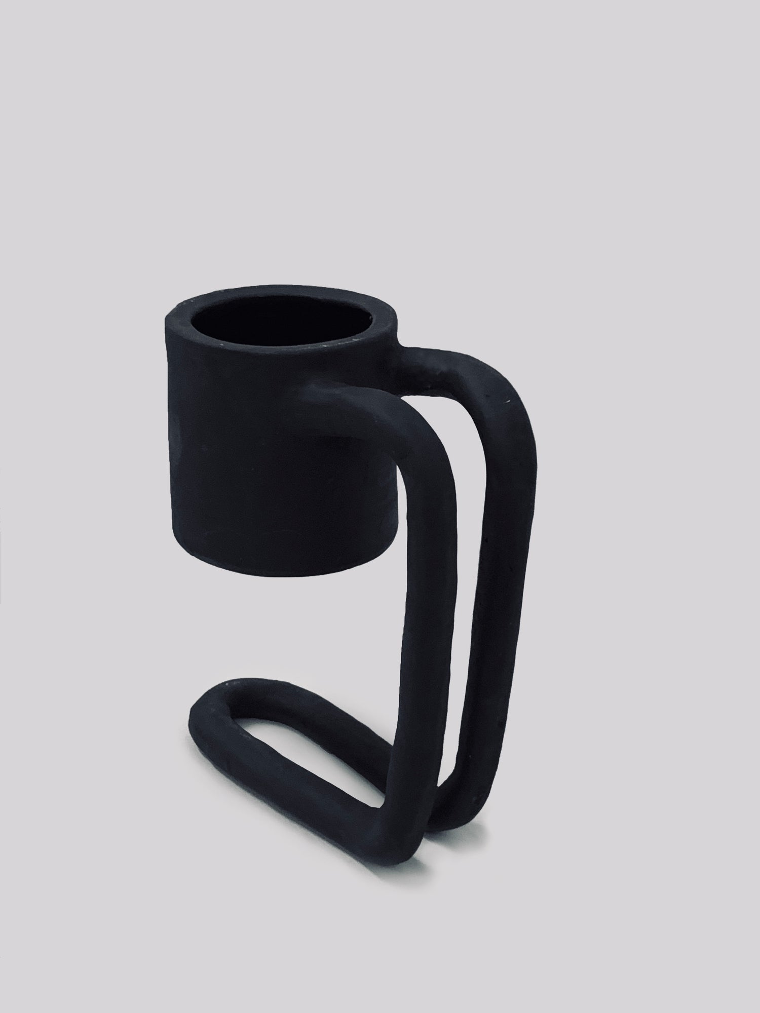 Black matte stoneware ceramic mug upon a tall fold over stand handle.