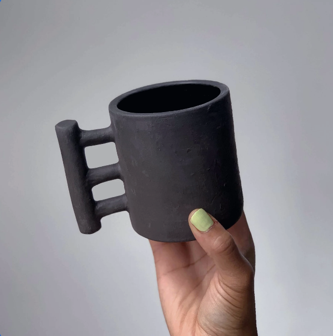 Black matte stoneware ceramic mug with three bars connecting to a thicker bar as the handle.