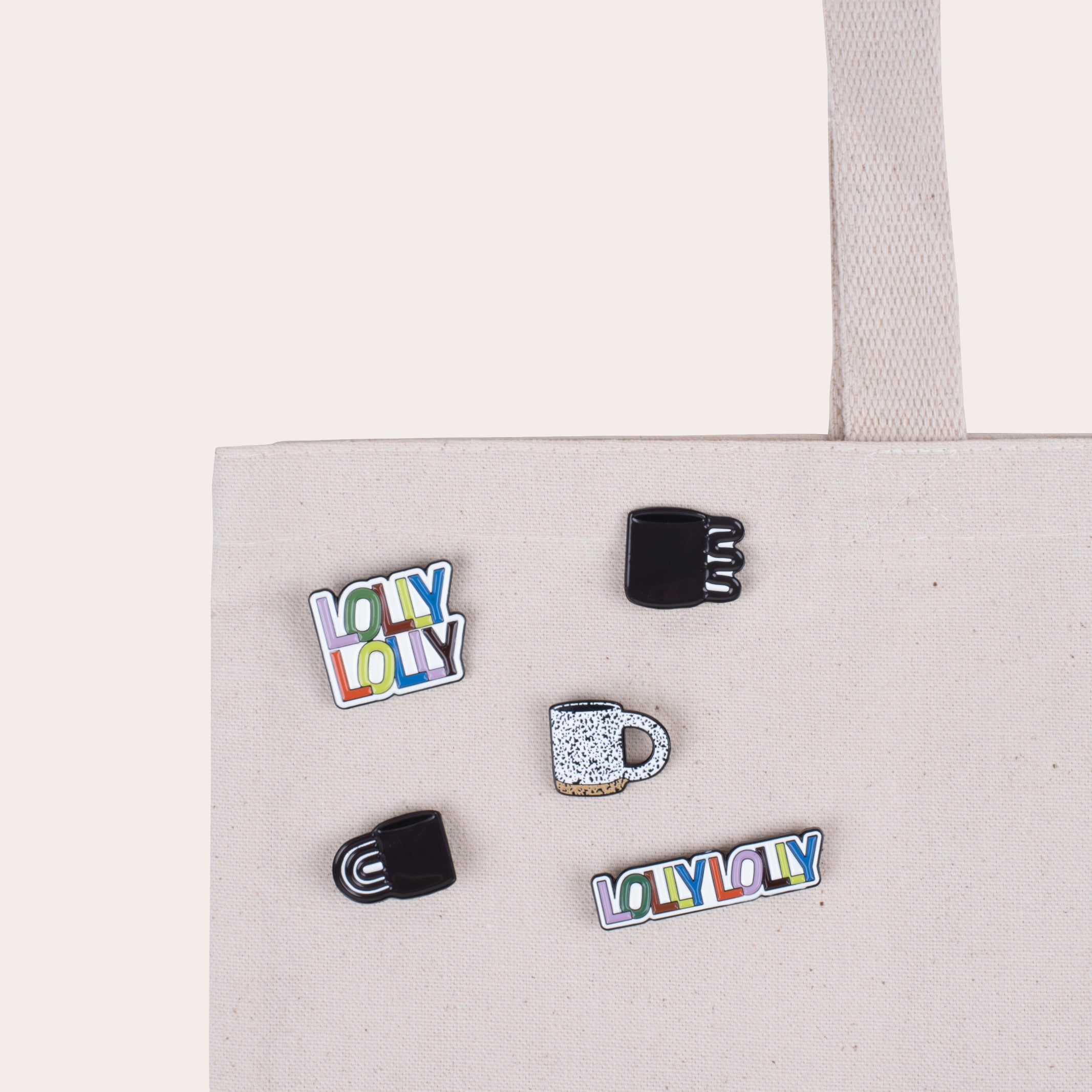 A soft enamel pin that reads &quot;Lolly Lolly Ceramics&quot; in a stacked formation with PVC rubber back.