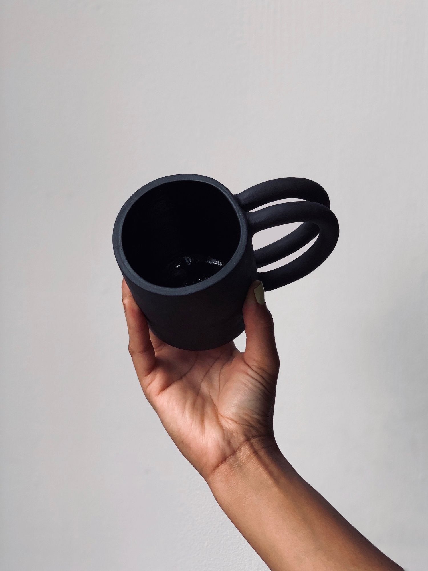Black matte stoneware ceramic mug with two circle handles.