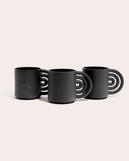 Black matte stoneware ceramic mug with a rainbow shaped handle.