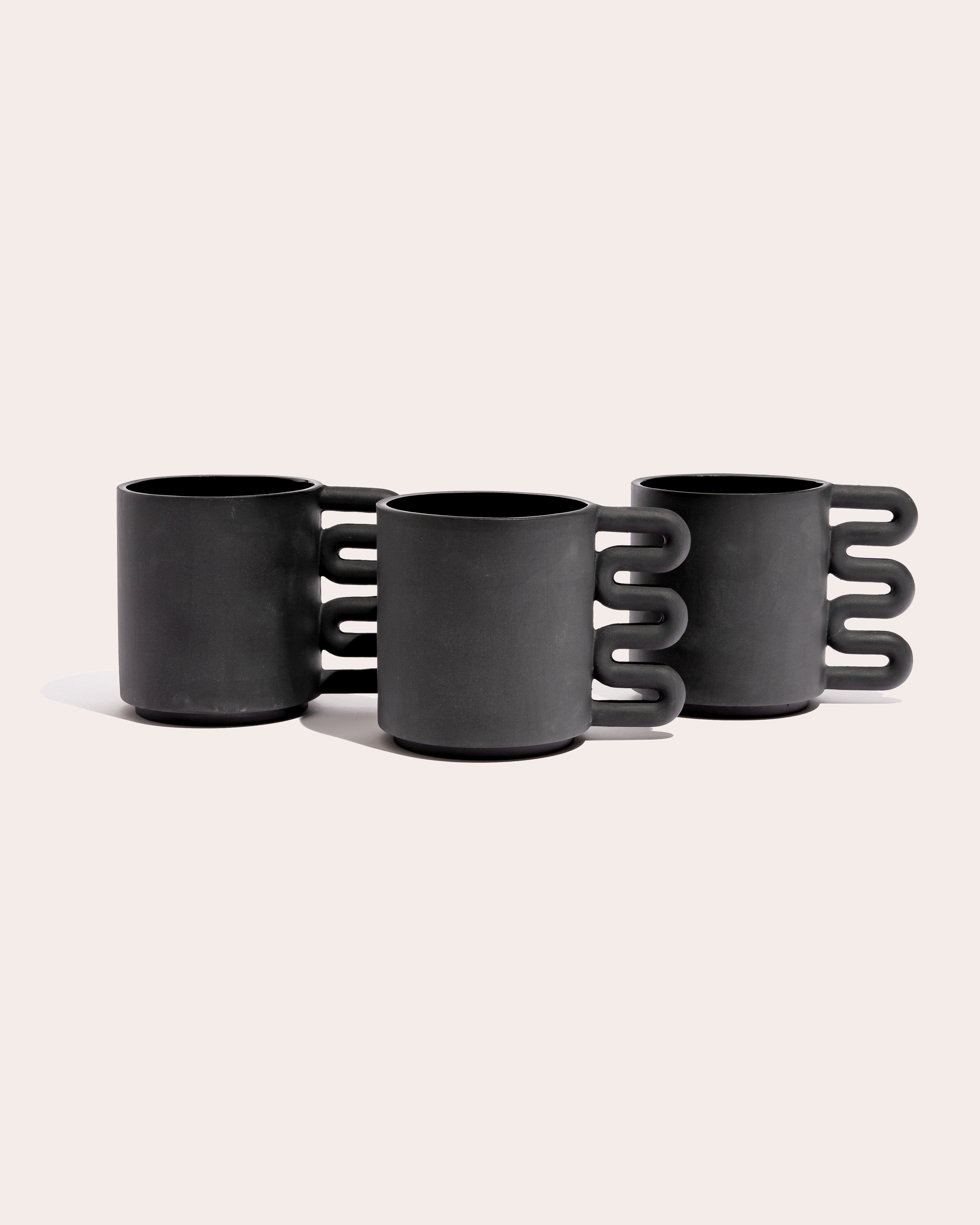 Black matte stoneware ceramic mug with a squiggle shaped handle.