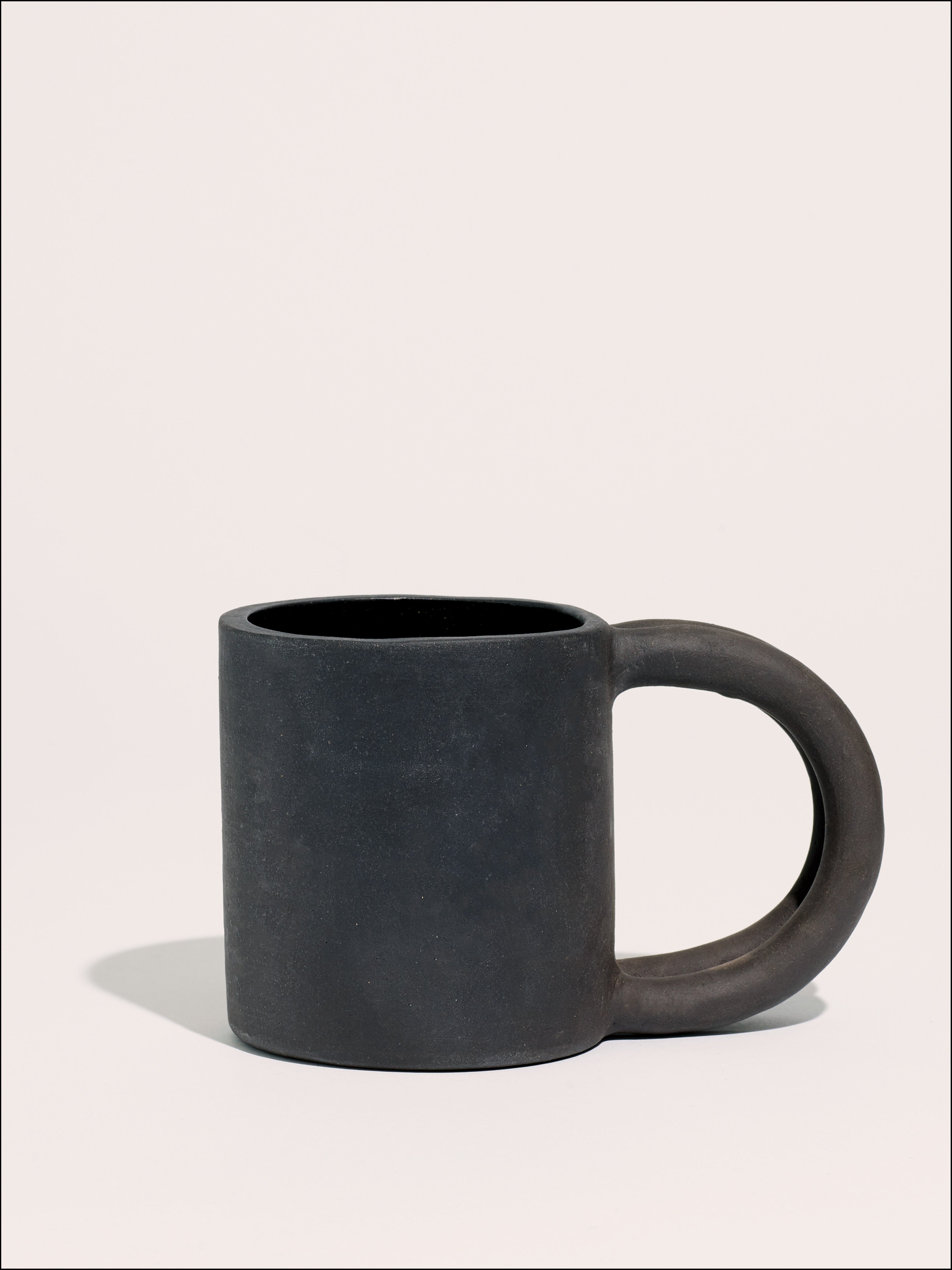 Black matte stoneware ceramic mug with two circle handles.