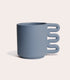Lolly Ceramics X Merit presents a blue matte stoneware ceramic mug with a squiggle shaped handle.