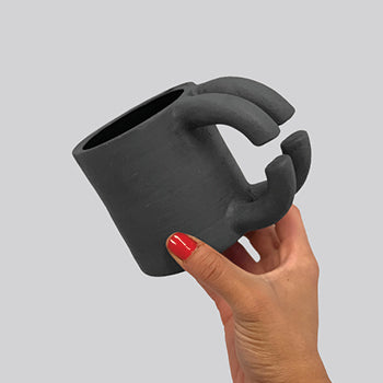 Black matte stoneware ceramic mug with two thick half split circle shapes that make the handles.
