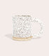 A speckled stoneware mug with a half circular handle. 